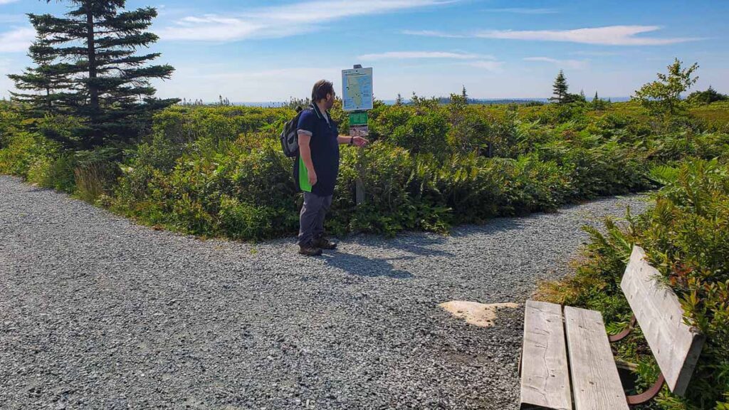 Man Looking at Trail Map at a fork inthe path at Kejimkujik National Park of Canada Seaside Adjunct